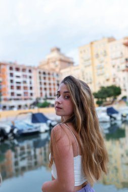 Yaz akşamları tropikal şehirde uzun saçlı sakin genç bir kadın setin üzerinde dikiliyor.