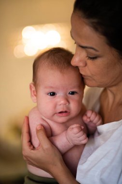Ekin manzarası sakin genç bir kadının gündüz vakti tapılası bebeği kucaklaması ve okşaması.