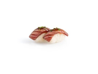 Yüksek kaliteli görüntü, beyaz bir arka planda izole edilmiş yeşil garnitürlü iki parça alevli ton balığı nigiri suşisini gösteriyor.
