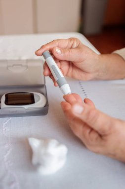 Bir kişi kan şekerini ölçmek için glukometre kullanmaya hazırlanır, diyabet kontrolü ve hipoglisemiyi önlemek için önemli bir günlük rutin.