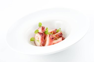 Sofistike sığır carpaccio tabağı, yeşil mikro yeşilliklerle süslenmiş beyaz yuvarlak bir tabakta, taze ve çekici bir görünüm sunuyor..