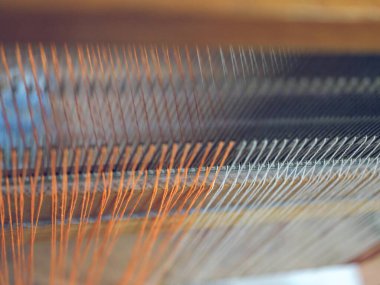 Bu görüntü, bir tekstil fabrikasındaki endüstriyel makineler üzerinde işlenen ipliklerin karmaşık detaylarını yakalar.