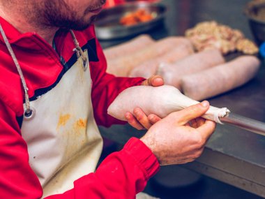 A detailed image capturing anonymous butcher skillfully filling sausage casing to prepare Sobrasada, a traditional Spanish sausage known for its distinct red color and rich flavor clipart