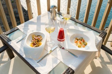 Tabakların yukarısından iştah açıcı deniz ürünleri tabakları sunuluyor şarap bardakları ve meyve suyu sürahisi ile deniz aşırı haute mutfağı restoranının terasında servis ediliyor.
