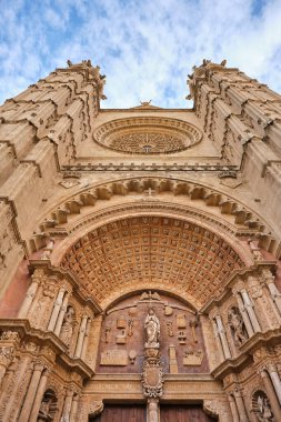 Mavi gökyüzüne karşı Katedral de Mallorca 'nın dekoratif cephesinin ayrıntılı görüntüsünün altından, bu tarihi simgenin karmaşık taş işçiliğini ve mimari ihtişamını gözler önüne seriyor.
