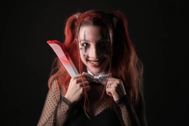 Esmer bir arkaplanda plastik bıçak tutan neşeli bir yüz ifadesi olan biri..