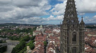 Yukarıdan, Bern, İsviçre 'nin çarpıcı bir şehir manzarasının hava aracı görüntüsü, tarihi binaların, yemyeşil ve dinamik bir ufuk çizgisi altında modern yapıların karışımını sergiliyor..