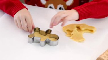 Bir çocuk, Noel temalı kurabiye hamuru keserken, aile ve geleneği ön plana çıkarırken, tatil büyüsü yaratıyor.