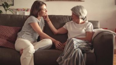 Genç bir kadın ve yaşlı annesinin samimi bir portresi bir kanepeye yakın oturuyor, görünür bir sevgi ve haz ile sohbet ediyorlar.