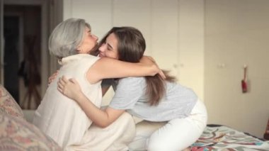 Bir anne ve kızı arasında bir yatakta kucaklaşan sahne, hem gülümseyen hem de mutluluk saçan bağlarının sevgisini yakalar, onların sevgi dolu ilişkilerini ve aile bağlarını vurgular.