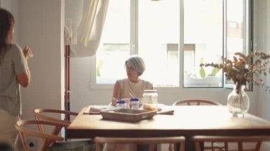 Kızı, mutfakta dururken annesini sıcak, sevgi dolu bir kucaklamayla kucaklıyor, anne gülümsüyor, bu aile anının tadını çıkarıyor, güçlü bağlarını ve karşılıklı aşklarını gösteriyor.