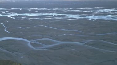 Sersemletici hava manzarası geniş bir dağlık arazide dolanan karmaşık bir nehir ağını gösteriyor. Doğal toprak tonlarıyla sarmalanmış hassas desenler yaratıyor.