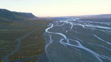 İç içe geçen nehirleri gösteren büyüleyici bir hava görüntüsü alacakaranlıkta geniş bir dağlık araziyi kesen, karmaşık doğaları ve arazinin saf güzelliğini gösteren bir görüntü.