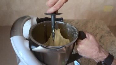 Bir kişinin eli modern bir mutfak mikseri işletiyor, geleneksel Roscon de Reyes pişirmek için hazırlanmış hamuru karıştırıyor, Epiphany sırasında kutlanan İspanyol Kralının Pastası.