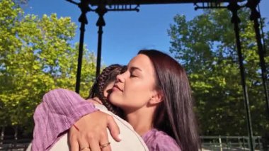 Lezbiyen bir çiftin, partneriyle kucaklaşıp güldüğü, güneşli bir zemin tarafından vurgulandığı bir an mutluluk ve sevgi yayıyor, LGBTQIA + ilişkilerini kutluyor.