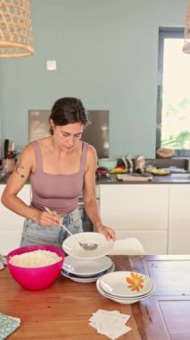 Bir kadın, mutfak tezgahında beyaz pirinci dikkatlice tabağa koyar ve sağlıklı beslenmeye odaklanmış bir aşçılık atölyesi sırasında sağlıklı bir yemek sunmaya çalışır.