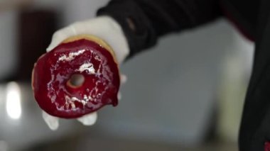 Parlak kırmızı bir jöleli el yapımı vejetaryen çöreğin yakın çekimi, vejetaryen ve sürdürülebilir yemek temaları için ideal siyah kıyafet giyen biri tarafından sergileniyor.