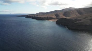 İnsansız hava aracı görüntüleri Kanarya Adaları 'nın engebeli kıyı şeritlerini gösteriyor, dingin mavi okyanusu vurguluyor ve gerçek zamanlı olarak çorak tepeleri dalgalandırıyor..