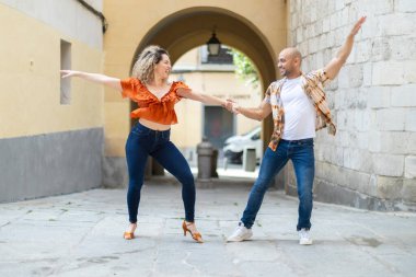 Kübalı dansçılar güneşli bir şehirde canlı bir Latin dansı gösterisine girişiyor. Erkek ve kadın el ele tutuşup dinamik pozlar veriyor, neşe ve enerjilerini sergiliyorlar..