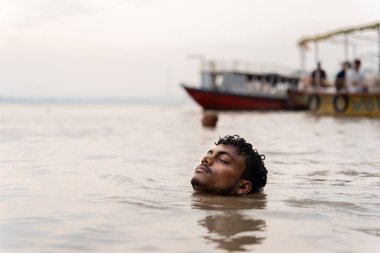 Hintli adam, Ganj nehrinin sularında gözleri kapalı meditasyon yapıyor ve dua ediyor.