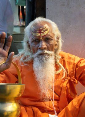 Hindistandaki sofu keşiş Sadhu, sakallı, beyaz saçlı ve yüzü boyalı kameraya bakarak vaaz veriyor.