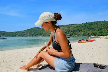 Lübnanlı genç bir kadın plajda güneş kremi sürüyor ve Tayland 'daki Koh Phi Adaları' nda bronzlaşıyor.