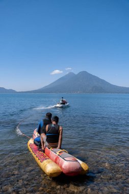 Genç İspanyol erkekler, Guatemala 'daki Atitlan Gölü' nde bir Hot Dog 'da su rekreasyonunun heyecanını sergiliyorlar.
