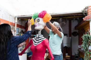 İki İspanyol kadın Ölüler Günü kutlamaları için bir iskelet süslüyor. Meksika 'da Dia de Muertos geleneği kavramı