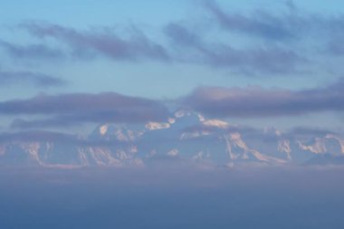 Mont Blanc 'ın yumuşak bulutlara sarılı kar kaplı tepelerinin büyüleyici manzarası, güneşin doğuşuyla dingin bir ışık gradyanı, Alpler' de büyüleyici bir doğal zaman atlaması sahnesi yaratıyor.