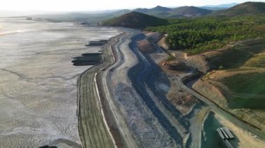 Hava görüntülerinde Huelva, İspanya 'daki Riotinto Madeni' nin geniş bir arazisi görülüyor. Virajlı yollar ve açık bir gökyüzünün altındaki ormanlık tepeler gösteriliyor.