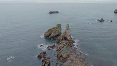 İspanya, Asturias 'ın dinamik ve engebeli kıyı şeridini gösteren gerçek zamanlı görüntüler. Kayalıklar, deniz taşları ve bulutlu gökyüzü..