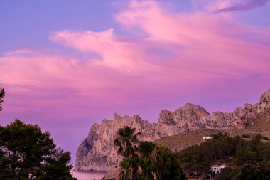 Günbatımı, Mallorca, Port de Pollenca yakınlarındaki Cala San Vicente 'deki engebeli Serra des Cavall Bernat uçurumlarına pembe bir parıltı saçar..