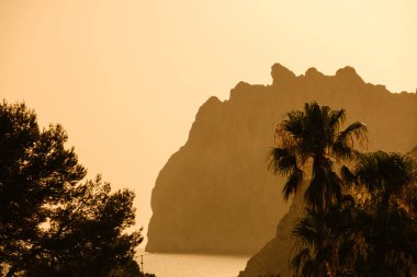 A captivating sunset view at Cala San Vicente, with the silhouette of Serra des Cavall Bernat ridge, overlooking Port de Pollenca in Mallorca. clipart