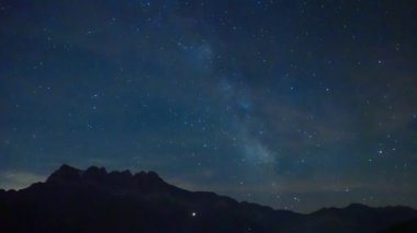 İsviçre Alplerindeki Dents du Midi zirvelerinin siluetinin üzerinde gece gökyüzüne uzanan Samanyolu 'nun büyüleyici görüntüsü sakin ve kozmik bir astrofotoğraf sahnesi.