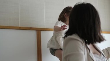 Genç bir çocuk ve annesi güneşli bir pencerenin yanında neşeli anlar yaşıyor ve doğal ışıklandırmada hassas bir aile etkileşimi sergiliyorlar..