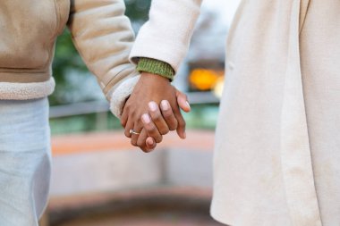 Nişanlı çiftin el ele tutuşup şehirde yürürken nişan yüzüklerini göstermeleri.