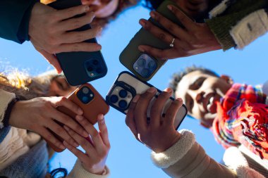 Akıllı telefonları bir arada tutan arkadaşlar, fotoğrafları ve videoları paylaşan, açık mavi gökyüzünün altında bir anlık bağlantının tadını çıkaran arkadaşlar.