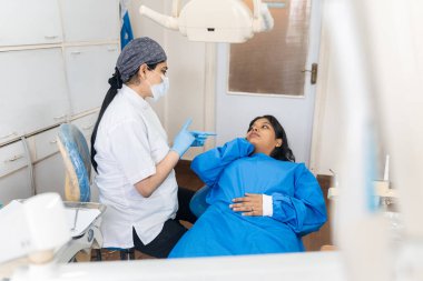 Hintli kadın dişçi klinikte kadın bir hastayla konuşuyor.