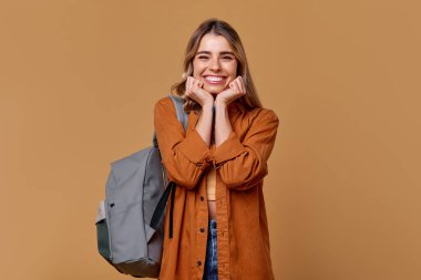 Uzun saçlı, şık giyimli ve son moda sırt çantalı neşeli genç bir kadın. Mutluluk saçıyor. Bu resim, çeşitli yaratıcı projeler için cazip, seyahat ve yaşam tarzı temalarını somutlaştırır.