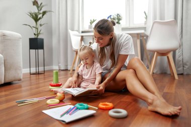 Sevgi dolu bir anne ve onun neşeli çocuğu arasında, yaratıcılıklarını ve hayal güçlerini ateşleyen renkli oyuncaklarla çevrili, sıcak ahşap bir zeminde, neşeli bir an paylaşılır.
