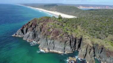 Engebeli uçurumlar, bereketli yeşillikler ve berrak bir gökyüzü altında ışıldayan mavi okyanusun yanında el değmemiş bir plajın yer aldığı Avustralya kıyı şeridinin nefes kesici bir görüntüsü..