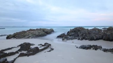 Kayalık bir Avustralya plajının büyüleyici zamanlaması, gün ışığından alacakaranlığa geçişi yakalıyor. Yumuşak okyanus dalgaları ve değişen ışık huzurlu bir sahil manzarası yaratır..