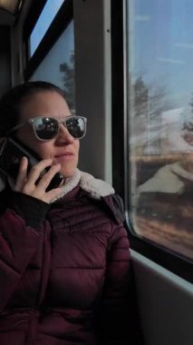 Güneş gözlüklü kadın güneşli bir tren yolculuğunda bir telefon görüşmesi yaptı..