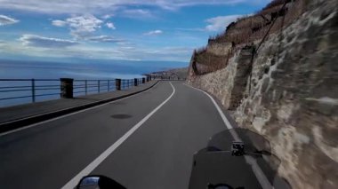 İsviçre 'nin Lavaux kentindeki uçurumlar boyunca uzanan kıvrımlı bir yol. Geneva Gölü de uzak mesafelere kadar uzanıyor. Dağlar, üzüm bağları ve su üzerindeki yansımalar geniş ve açık bir manzara yaratır..