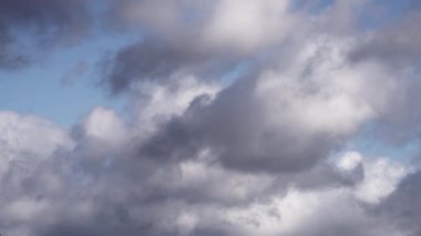 Yumuşak, tüylü bulutların rahatlatıcı zaman dilimi canlı mavi bir gökyüzünde yavaşça sürükleniyor. Bulut katmanları, dinamik ve dinamik bir gökyüzü sunan güzel bir kontrast oluşturuyor..