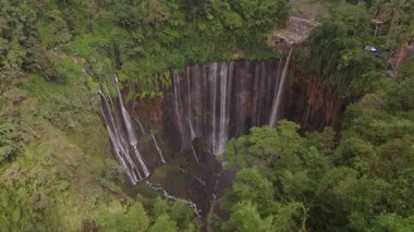 Nefes kesici bir dron görüntüsü Endonezya 'nın Java kentindeki yemyeşil yemyeşil bir şelaleyi yakalar. Havadan bakış açısı doğanın ihtişamını ve güzelliğini vurgular..