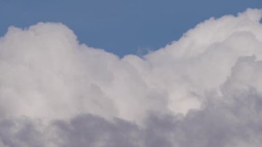 Kümülüs bulutlarının açık mavi gökyüzüne karşı dinamik hareketini ve dönüşümünü gösteren çarpıcı bir zaman dilimi videosu..