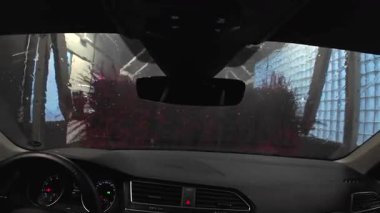 Otomatik oto yıkama sırasında arabanın içindeki gerçek zamanlı video, ön cam görüntüsünü suyla ve hareket halindeki fırçalarla gösteriyor.