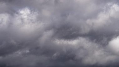 Yoğun gri bulutların büyüleyici zamanlaması dönen ve yer değiştiren, ara sıra mavi gökyüzünü gösteren. Sahne, yumuşak ışığın filtrelediği dramatik bir hava değişimi yakalıyor..