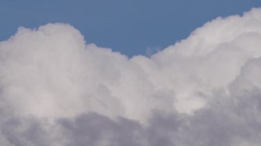 Kümülüs bulutlarının berrak mavi gökyüzüne karşı durgun hareketlerini gösteren büyüleyici bir zaman dilimi videosu doğal güzelliği ve atmosferik dinamikleri gerçek zamanlı olarak gösteriyor..